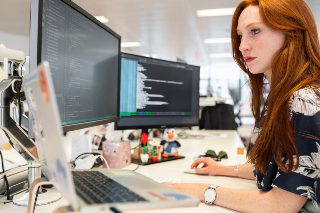 pexels photo 3861958 A focused female software engineer coding on dual monitors in a modern office.